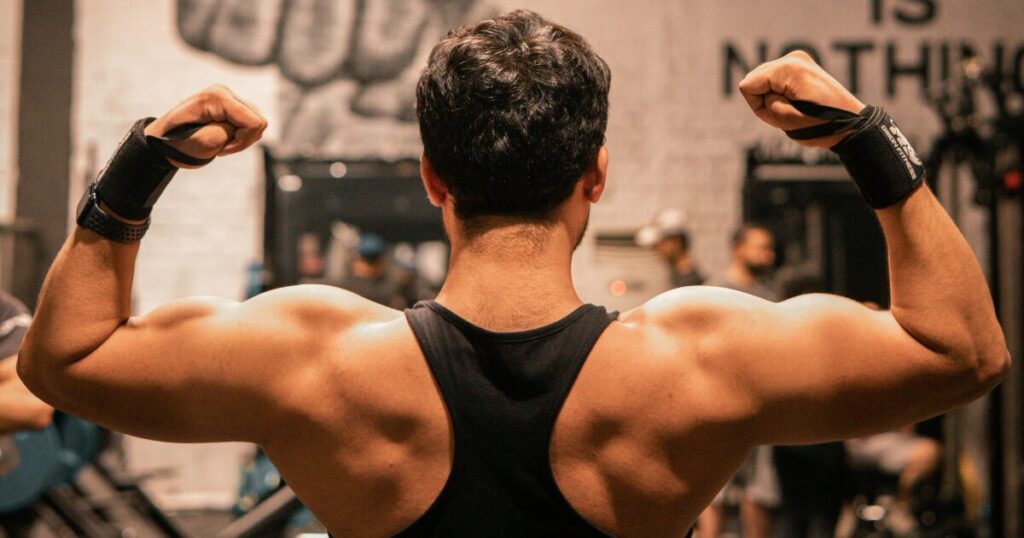 ジムでダブルバイセップスポーズを取る男性の背中